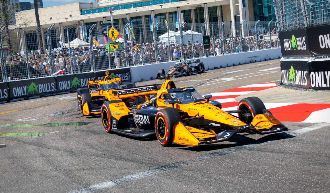 Two papaya-and-black Arrow McLaren cars running nose to tail through a corner