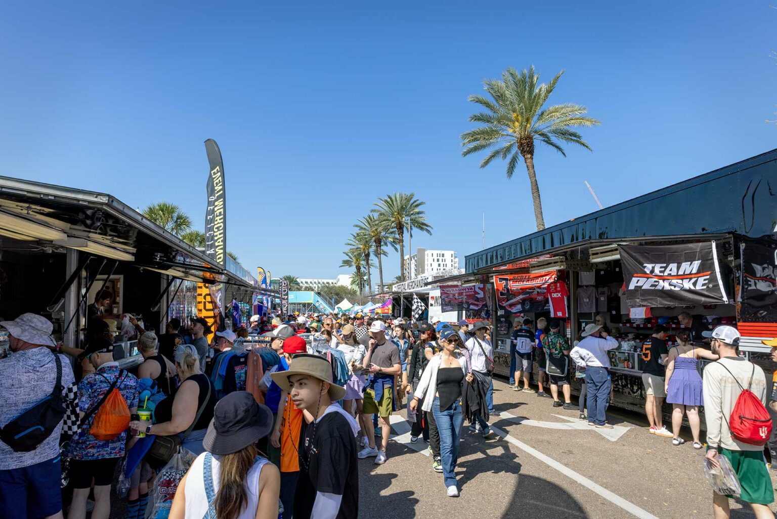 Fans browsing team merchandise trailers along the paddock midway