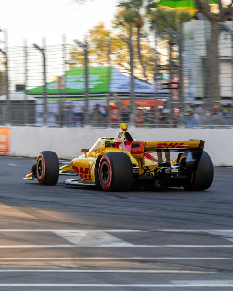 Rear view of the No. 10 DHL car accelerating away on red-walled tires